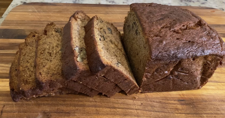 Banana bread loaf sliced and laying on a wooden cutting board