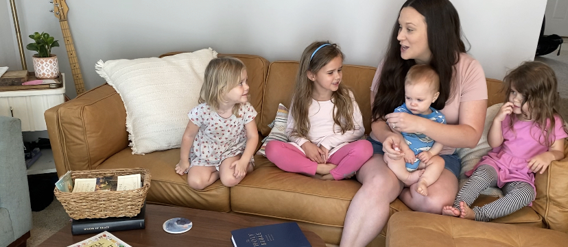 Homeschooling mother sitting on a couch with her children singing together