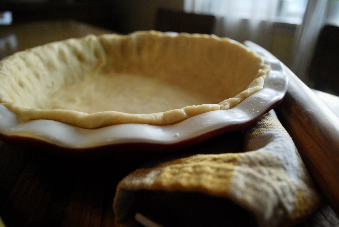 All butter pie crust sitting on a kitchen towel with a rolling pin beside it